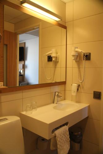a bathroom with a sink and a mirror and a toilet at Hotel Savoy in Mariehamn