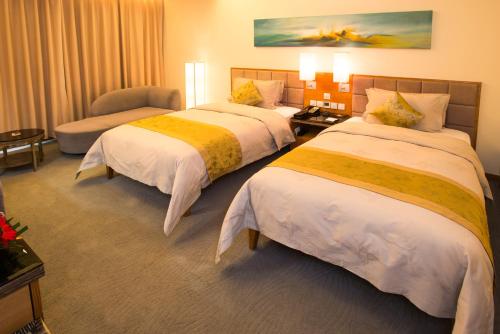 a hotel room with two beds and a chair at Shenzhen Longgang Rivan Hotel in Longgang