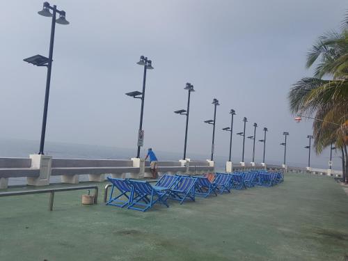 a row of blue chairs on a pier with the ocean at Bangsaen Royal Beach by Preyaluk in Bangsaen