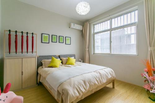 Un dormitorio con una cama con almohadas amarillas y una ventana en Xi'an Lianhu·Longshou Business Circle· Locals Apartment 00154940 en Xi'an