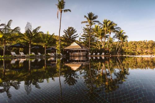 a resort with palm trees and a pool of water at Orpheus Island Lodge in Orpheus Island