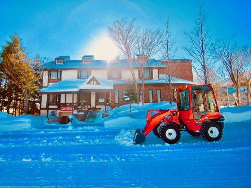 a red tractor covered in snow in front of a house at Appi Life is Beautiful in Hachimantai