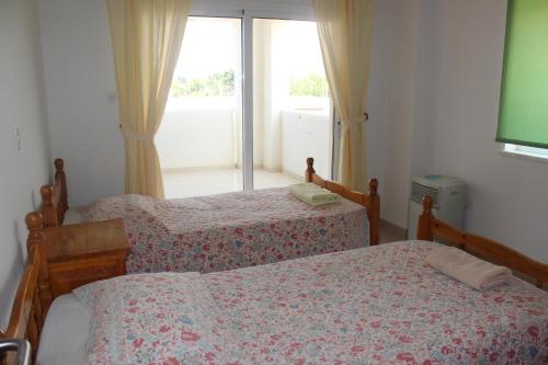 a bedroom with two beds and a window at Galatia's Court in Paphos City