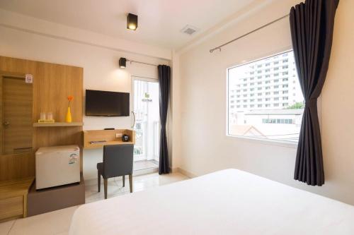 - une chambre avec un lit, un bureau et une fenêtre dans l'établissement Bedtime Pattaya, à Pattaya
