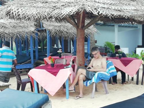 a man sitting in a chair on the beach at Hotel Universal Beach in Hikkaduwa
