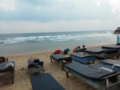 a beach with blue tables and people in the ocean at Hotel Universal Beach in Hikkaduwa