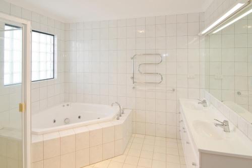 a white bathroom with a tub and a sink at Bayside Beauty in Busselton