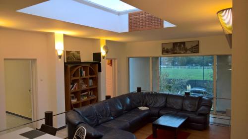 a living room with a leather couch and a skylight at Bambou & Olivier Chambres in Roubaix