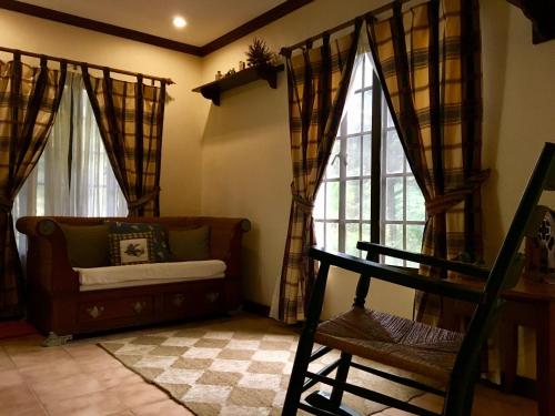 ein Wohnzimmer mit einem Sofa und Fenstern in der Unterkunft La Famille Canyon Woods Tagaytay in Balibaguhan