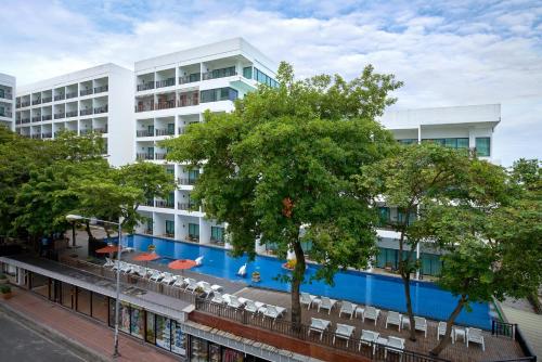 a large building with a swimming pool in front of it at Cosy Beach Hotel - SHA Extra Plus in Pattaya South