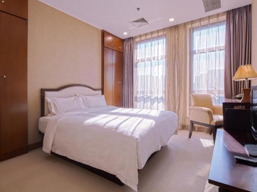 a bedroom with a large white bed and a television at Dalian Asia Pacific Service Apartment (Former Somerset Harbour Court Dalian) in Dalian