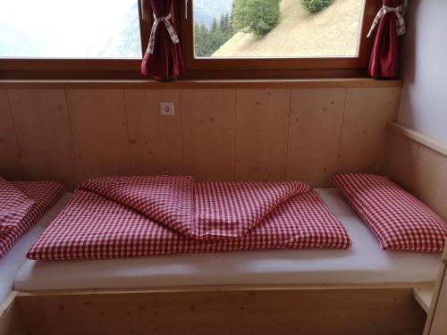 a bench in a room with three red and white pillows at Aussermairhof in Campo Tures