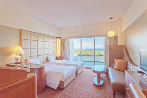 um quarto de hotel com uma cama e uma grande janela em Okinawa Kariyushi Beach Resort Ocean Spa em Onna