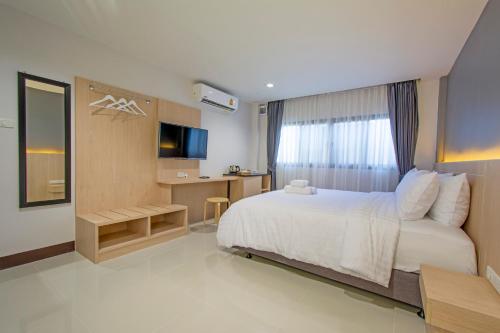 1 dormitorio con 1 cama blanca grande y escritorio en Happiness Guesthouse en Pak Chong