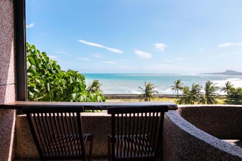 two chairs sitting on a balcony looking out at the ocean at Pasa in Fushan