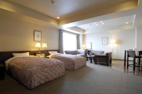 a hotel room with two beds and a living room at Karuizawakurabu Hotel 1130 Hewitt Resort in Tsumagoi