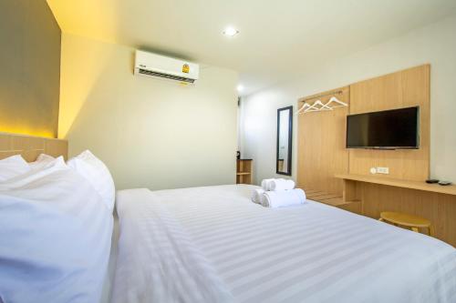 a bedroom with a large white bed with a flat screen tv at Happiness Guesthouse in Pak Chong
