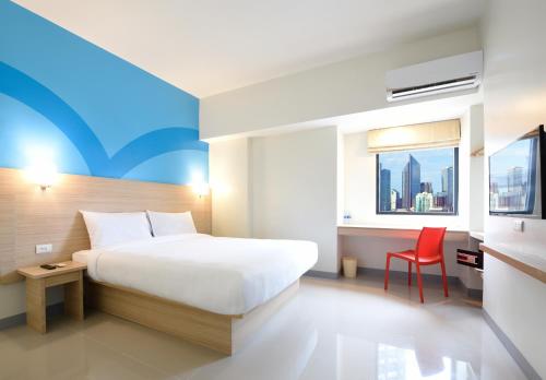una camera d'albergo con letto e sedia rossa di Hop Inn Hotel Tomas Morato Quezon City a Manila