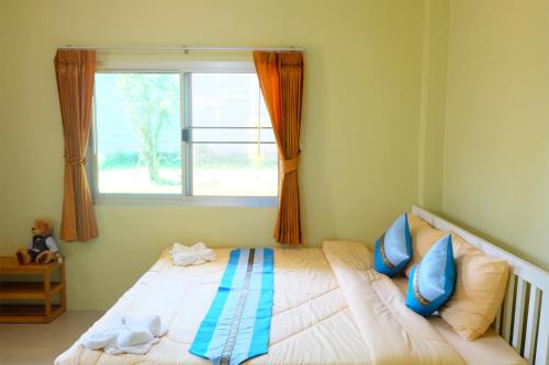 a bedroom with a bed with blue pillows and a window at Akantuka Homestay in Chanthaburi
