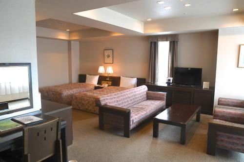a hotel room with a bed and a couch at Karuizawakurabu Hotel 1130 Hewitt Resort in Tsumagoi