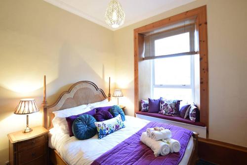 sypialnia z łóżkiem z poduszkami i oknem w obiekcie ALTIDO Classic 2BR Apartment with Castle Views in Old Town w Edynburgu