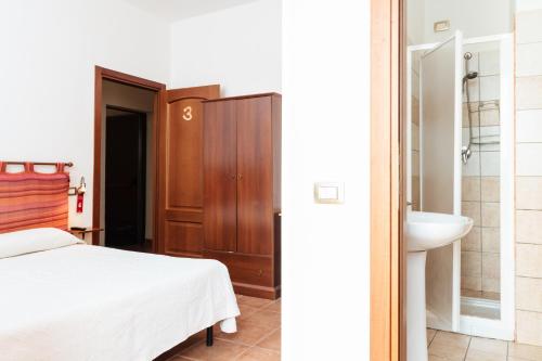 a bedroom with a bed and a bathroom with a sink at La Mezzanella Guesthouse in Porto Torres