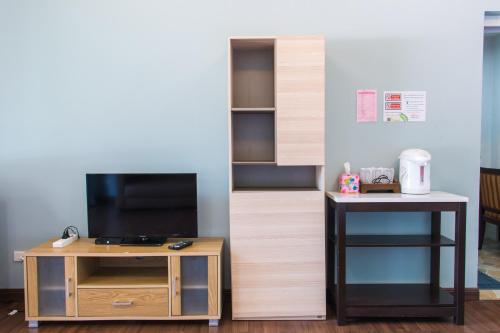 a room with a tv and a table with a tv stand at Akantuka Homestay in Chanthaburi