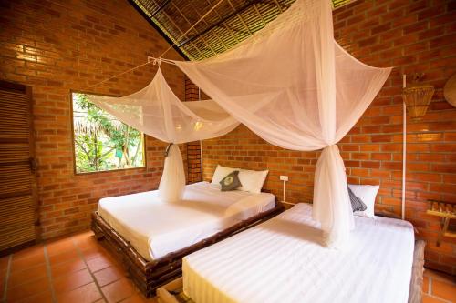 a bedroom with two beds with mosquito nets over them at Mekong Rustic Cai Be in Cai Be