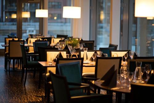 a dining room with tables and chairs with lights at Hotel Öresund Conference & Spa in Landskrona