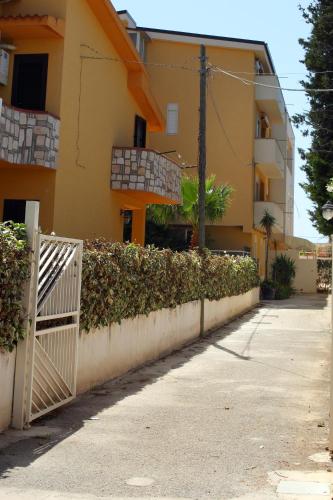 a fence in front of a building with a hedge at B&B Le Dune Beach in San Leone