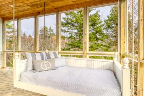 a bed in a screened porch with windows at Sea At Last in Phippsburg