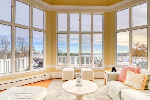 a living room with large windows and a table at Sea At Last in Phippsburg