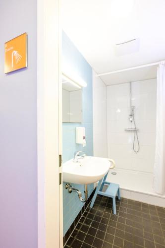 a bathroom with a white sink and blue tiles at HI Munich Park Youth Hostel in Munich
