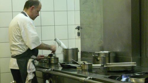 a man standing in a kitchen preparing food at Hostellerie d'Héloïse Logis in Cluny