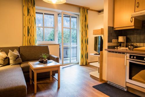 a living room with a couch and a table at Appartement Mühle - including Summercard, Sauna, Kaprun's largest private garden with panoramic view in Kaprun