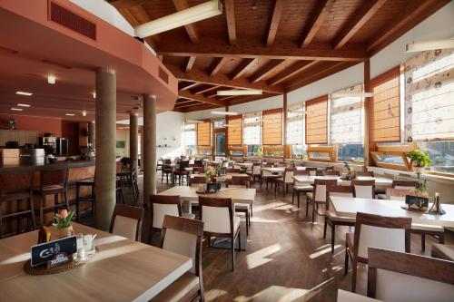 a restaurant with wooden ceilings and tables and chairs at Wellness Hotel Říčky in Říčky