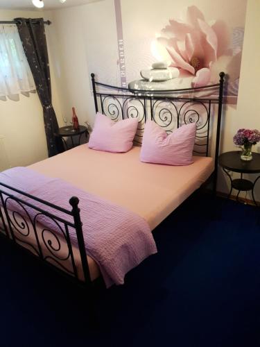 a bedroom with a black bed with pink pillows at Eifelflair in Retterath