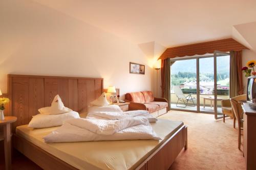 a bedroom with a bed and a living room at Hotel Kronplatz in Valdaora