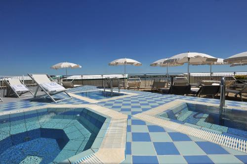basen z leżakami i parasolami na terenie ośrodka w obiekcie Hotel Gradara w mieście Bellaria-Igea Marina