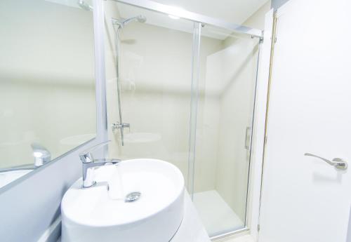 a white bathroom with a shower and a sink at Sol Playa in Valencia