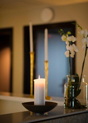 a candle on a counter with a vase with flowers at Hotel Öresund Conference & Spa in Landskrona
