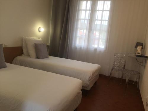 a hotel room with two beds and a window at Hôtel Castel Saint Anne in Le Castellet
