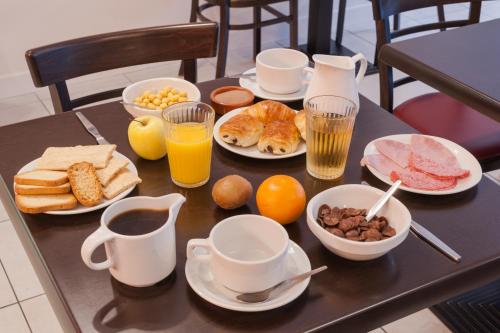 a table with breakfast foods and drinks on it at The Originals City, Hôtel Le Savoy, Caen (Inter-Hotel) in Caen