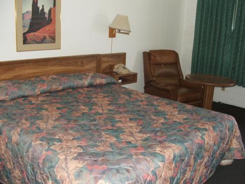 a hotel room with a bed and a chair at Arizona Inn in Kingman