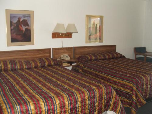 a hotel room with two beds and a lamp at Arizona Inn in Kingman