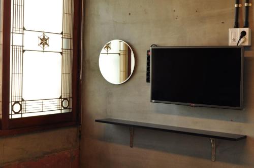 a television mounted on a wall next to a window at Mido Hostel in Seogwipo