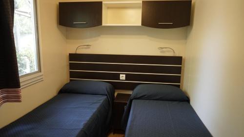a small bedroom with two beds and a desk at Camping Village Adriatico Giulianova in Giulianova