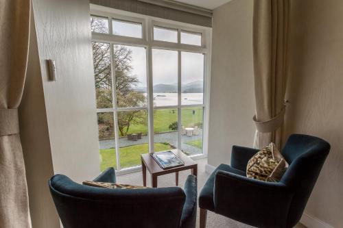 a living room with two chairs and a large window at Storrs Hall Hotel on the shore of Lake Windermere in Bowness-on-Windermere