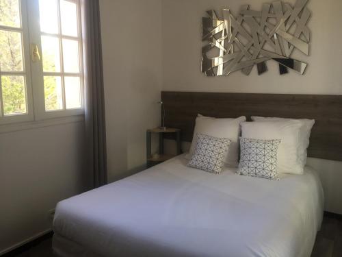 a bedroom with a bed with white sheets and pillows at Hôtel Castel Saint Anne in Le Castellet