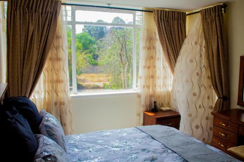a bedroom with a bed and a large window at MYSECONDHOME in Harare